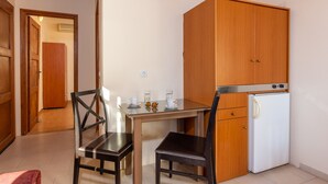 Una pequeña kitchenette con un refrigerador, un mueble de madera y una mesa con sillas.