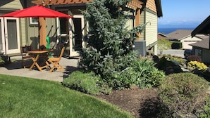 Ein Haus mit einer Holzterrasse, einem roten Sonnenschirm und einem Weihnachtsbaum.