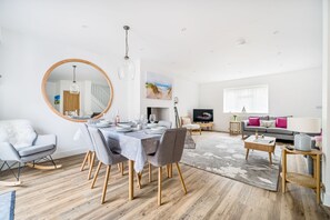 A modern living room with a dining area, a large mirror, and a television. - Jasmine Cottage - sleeps 5 guests  in 3 bedrooms (Thornham)