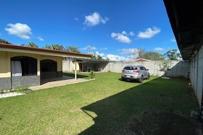A residential property with a covered patio, a car parked in the driveway, and a well-maintained lawn.
