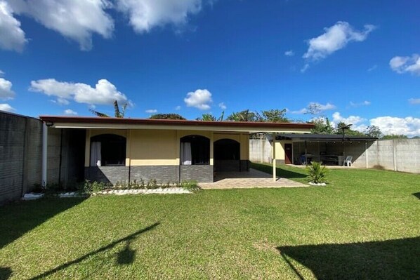 A two-story house with a covered patio, a well-maintained lawn, and a clear blue sky.