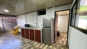 Une cuisine de taille réduite, équipée d’un réfrigérateur, d’un évier et d’un petit plan de travail.