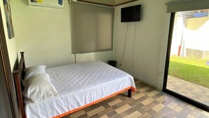 Une chambre avec un lit, un téléviseur fixé au mur et une fenêtre.