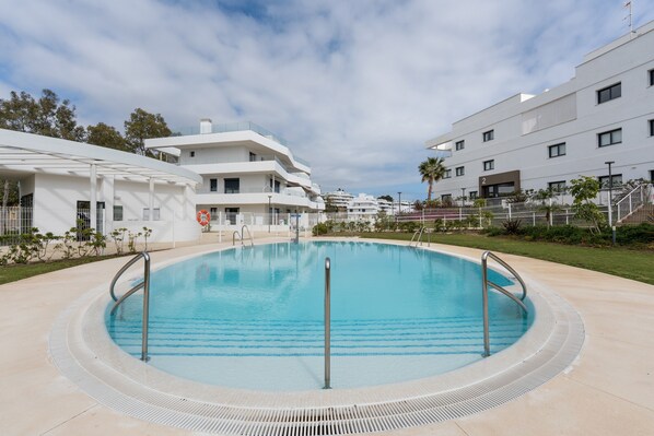 Una piscina con barandilla de metal, rodeada de un área pavimentada y edificios modernos.