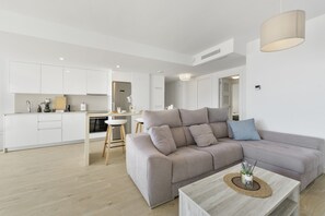 Ein modernes Wohnzimmer mit Sofa, Couchtisch und einem Küchenbereich im Hintergrund.