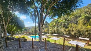 Zona de piscina con sillones de descanso, bañera de hidromasaje y vistas al bosque circundante.