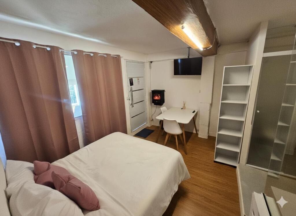 Un dormitorio con cama, escritorio, televisor y armario.