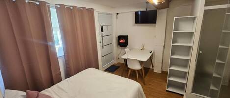 Un dormitorio con cama, escritorio, televisor y armario.