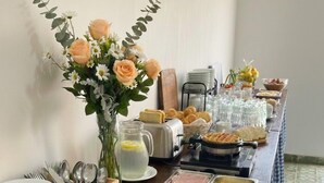 Montaje de bufé con diferentes alimentos, utensilios y un jarrón decorativo.