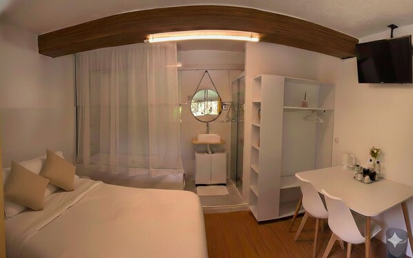 A bedroom with a bed, a desk, a mirror, and a wardrobe. - SUITES - Românticas na Natureza para Adultos (Itapecerica da Serra)