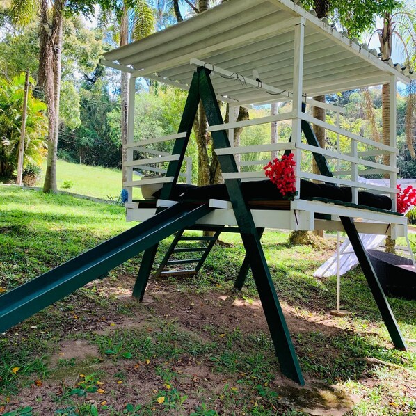 A white pergola with a green ladder and a black swing set. - SUITES - Românticas na Natureza para Adultos (Itapecerica da Serra)