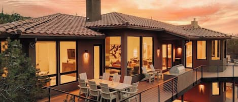 Una casa moderna con terraza, ventanas amplias y chimenea.
