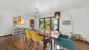 Un comedor moderno con una mesa de madera, sillas amarillas y verde azulado, y una lámpara colgante.