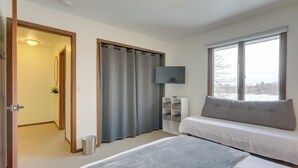 Un dormitorio con cama, ventana, televisor y mesita de noche.