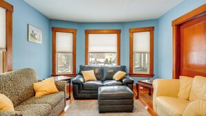 A living room with a blue wall, a black leather sofa, a yellow sofa, and a patterned armchair. - 9 Mi to Wachusett Mtn! Family Base w/ Porch (Fitchburg)