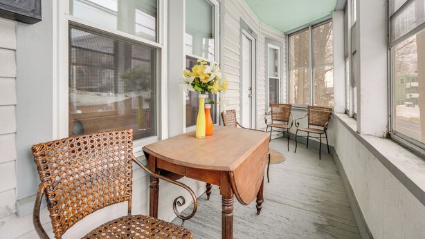 A covered porch with a wooden table and wicker chairs, a vase with flowers, and large windows. - 9 Mi to Wachusett Mtn! Family Base w/ Porch (Fitchburg)