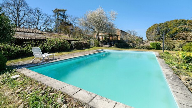 A rectangular swimming pool with a tiled deck, surrounded by greenery and trees. - Gîte de Marlas - Ariège (Rieucros)