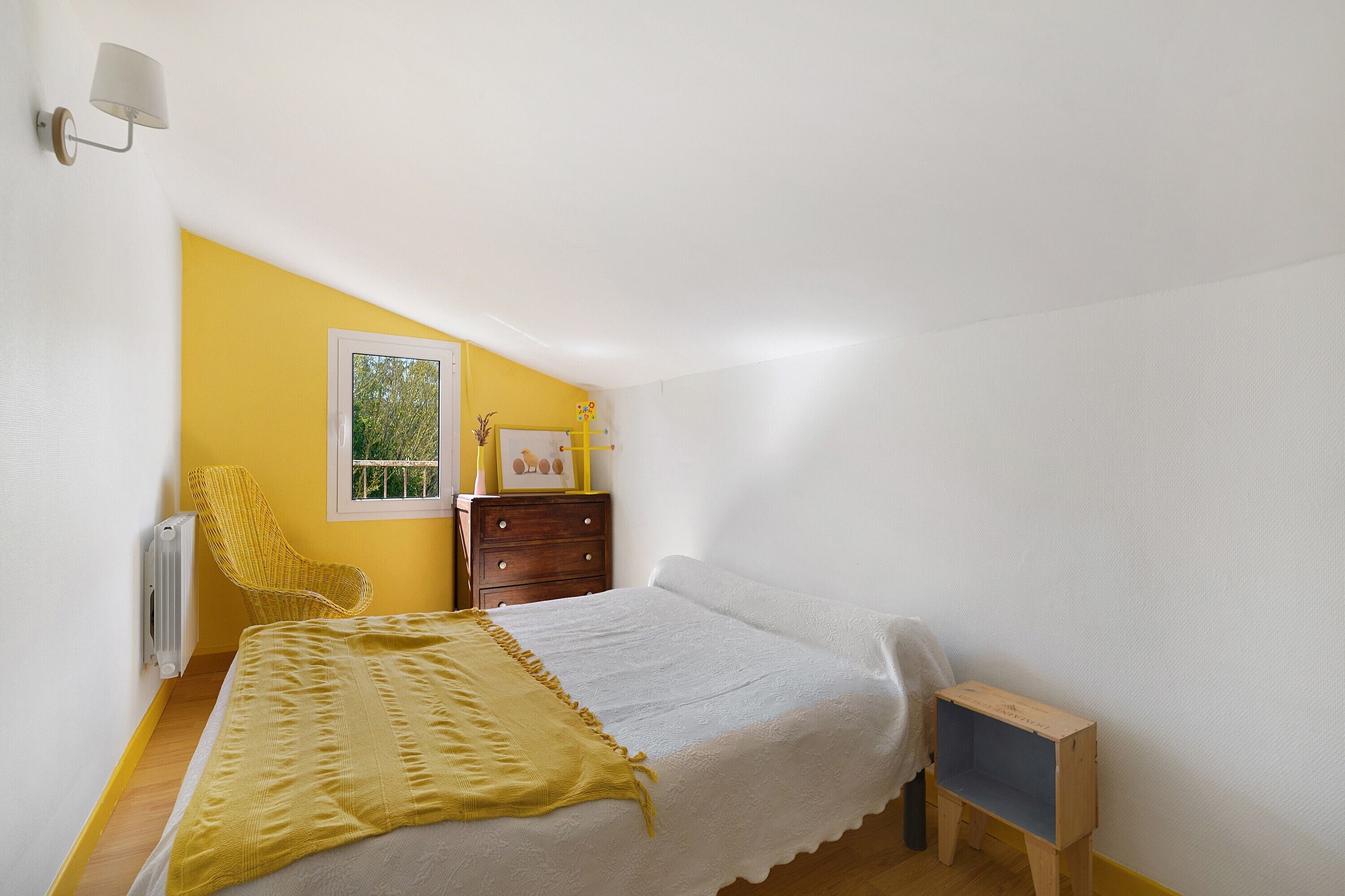 Un dormitorio con una cama, una silla, un tocador y una mesita.