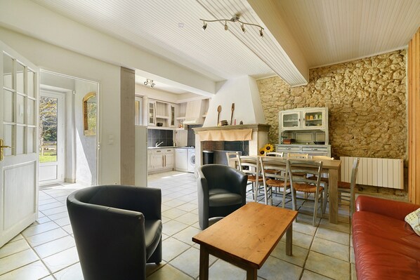 A spacious living area with a dining table, chairs, a sofa, and a kitchen in the background.