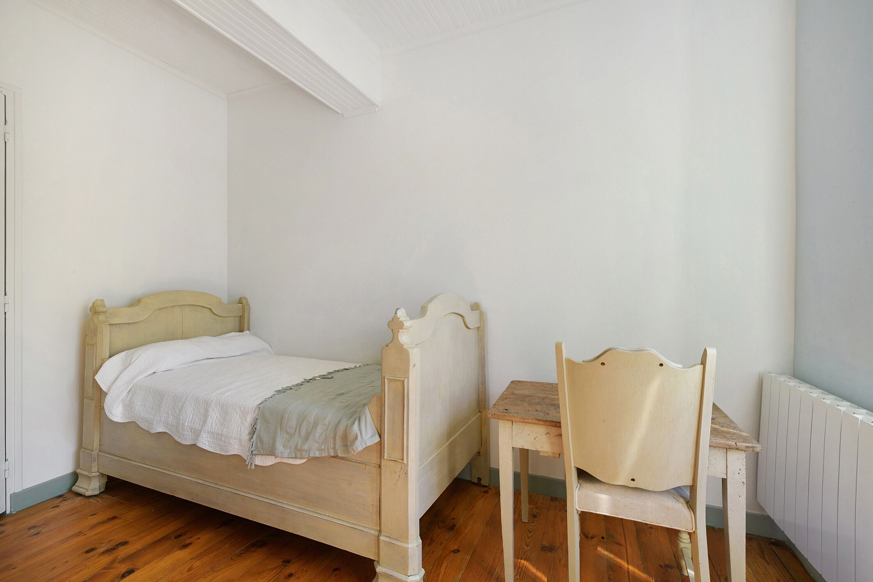 Ein Schlafzimmer mit einem hölzernen Bett, einem Holzstuhl und einer Heizung.