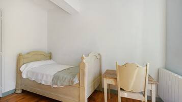 Ein Schlafzimmer mit einem hölzernen Bett, einem Holzstuhl und einer Heizung.