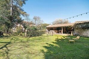 A rustic outdoor seating area with wooden furniture, a pergola, and a stone wall. - Bed and Breakfast 'L'Étable' with Shared Terrace, Shared Garden and Wi-Fi (Rieucros)