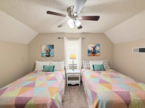 A bedroom with two beds, a ceiling fan, a nightstand, and two wall art pieces. - A-frame of Mind Lakefront Home (Rocky Mount)