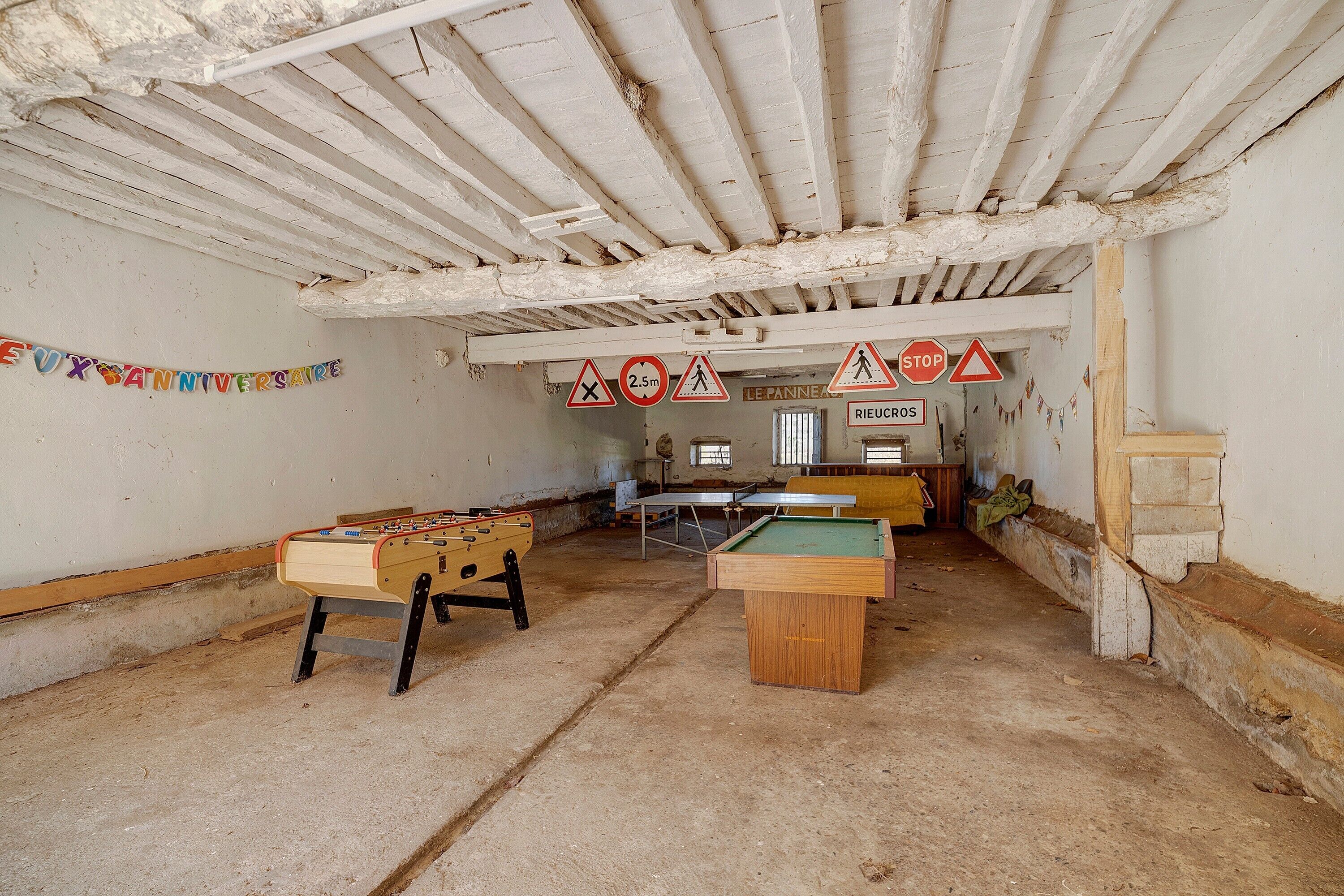 Una habitación con mesa de futbolín, mesa de billar y un cartel que indica un límite de altura de 2,5 metros.