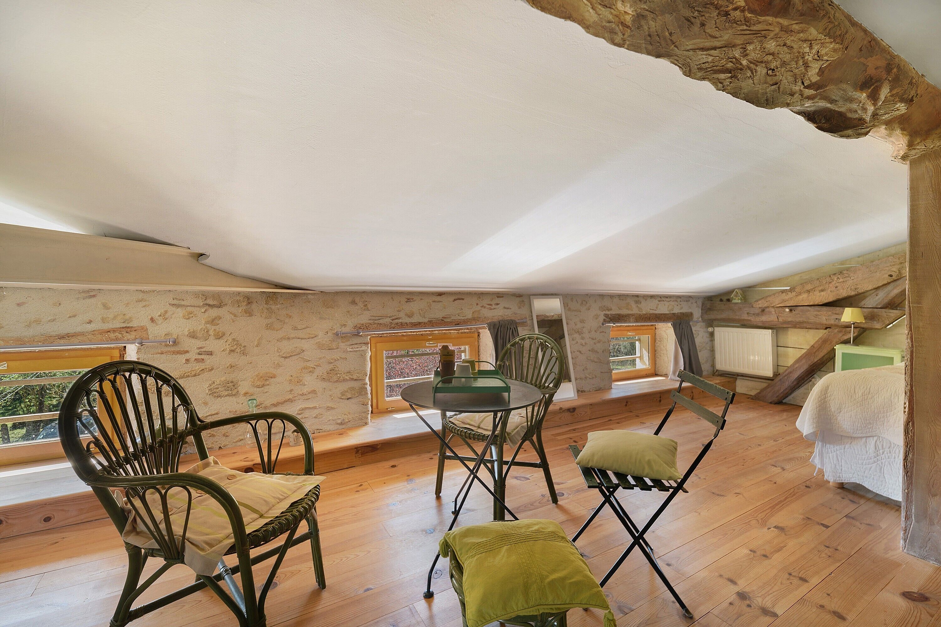 Une chambre située dans un espace de type « loft », avec un plafond en pente, un plancher en bois et une vue par une fenêtre.