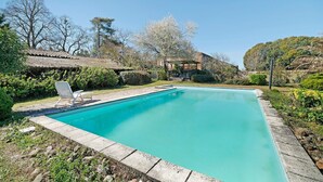 Une piscine rectangulaire à l’eau d’un bleu limpide, bordée de pierres, et dotée d’une chaise longue.