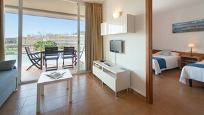 Ein Hotelzimmer mit Balkon, Schreibtisch, Bett und Fernseher.