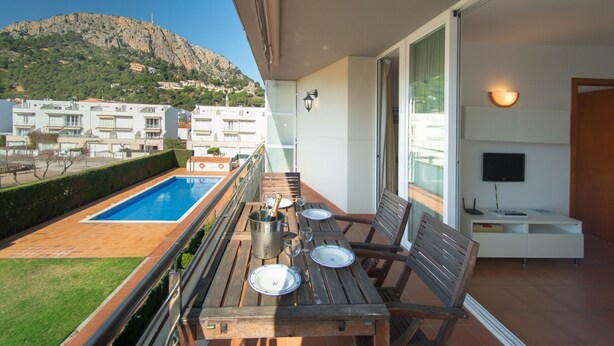 Ein Balkon mit Pool, Holzmöbeln und einem Fernseher.