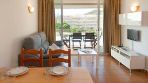 Ein modernes Hotelzimmer mit Balkon, Essbereich und Fernseher.