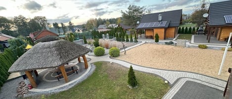 Zona residencial con un patio arenoso, un quiosco de madera y una casa con paneles solares.