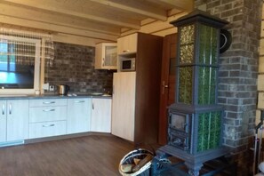 A kitchen with wooden cabinets, a microwave, and a green-tiled stove.