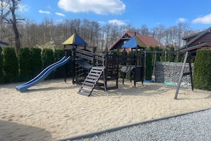 A playground with a slide and climbing structures. - Holiday cottages with fireplace, right by the lake (Lubrza)