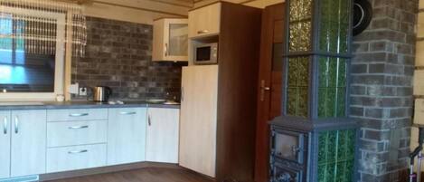 Una cocina con armarios de madera, un microondas y una estufa con azulejos verdes.