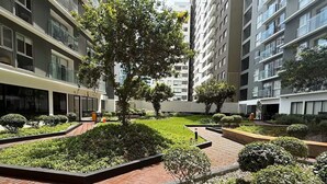 A modern urban courtyard with neatly landscaped gardens, brick pathways, and tall residential buildings. - APT GRAÑA - MAGDALENA  (Lima)