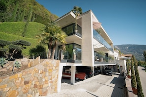 Une maison moderne à deux étages, dotée d’un mur en pierre, d’un garage et d’une allée.