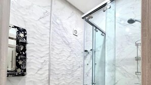 Une salle de bain avec une douche à parois de verre, un lavabo blanc et des toilettes.
