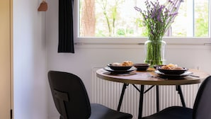 Una mesa de comedor con un jarrón de flores, dos platos de comida y dos sillas.