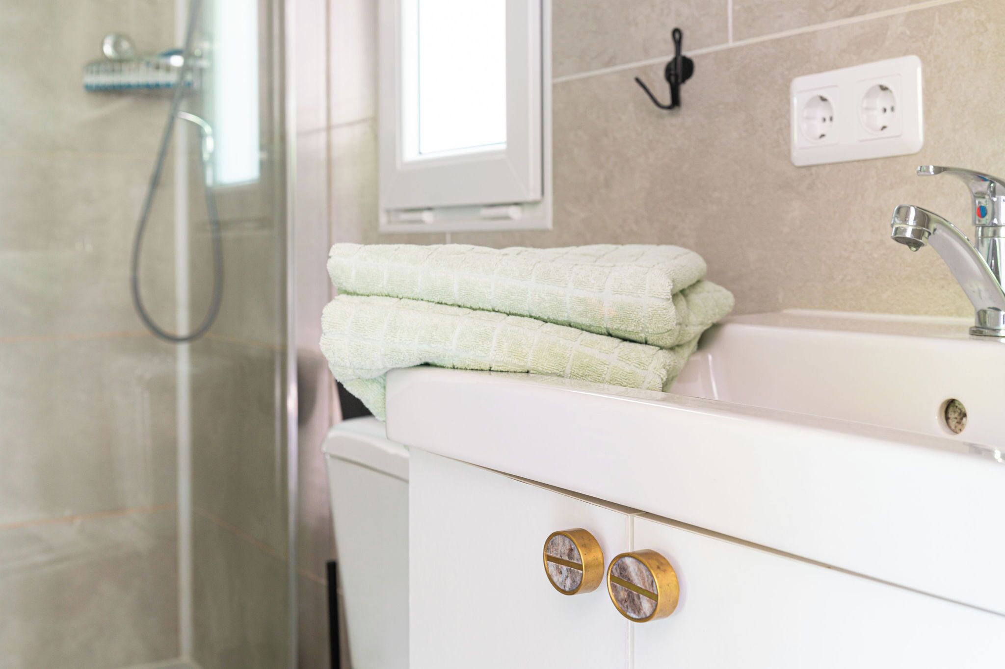 Une salle de bain avec un lavabo blanc, un miroir et un porte-serviettes.