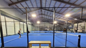 Una cancha de tenis interior con un banco de madera y una red.