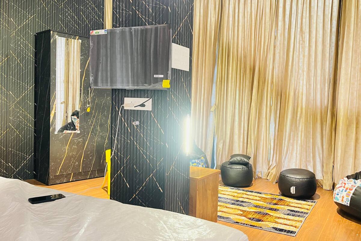 Een moderne slaapkamer met een bed, een zwarte relaxfauteuil, een klein houten tafeltje en een kamerkleed met een patroon.