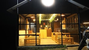 A restaurant with a warm interior, wooden furniture, and a large illuminated sign above the entrance. - Airas Resort (Kodaikanal)