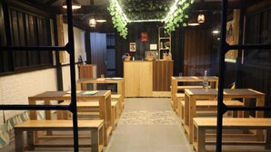 A restaurant interior with wooden tables and benches, a central counter, and decorative greenery. - Airas Resort (Kodaikanal)