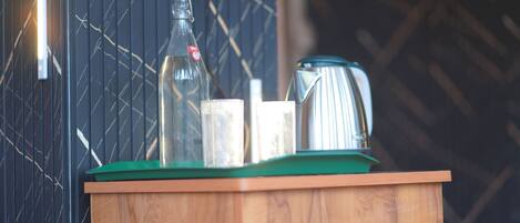 A wooden cabinet with a green top, a glass bottle, a metal pitcher, and a white container.