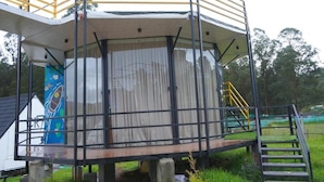 A modern, enclosed structure with a glass facade, metal railings, and a staircase leading up. - Airas Resort (Kodaikanal)