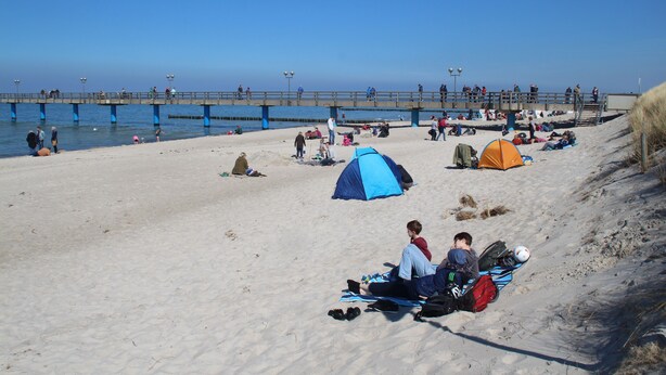 A beach with tents and people relaxing.