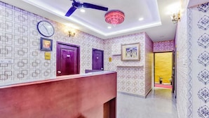 A reception area with patterned walls, a reception desk, a ceiling fan, and a chandelier. - Hommetree T Nagar (Chennai)